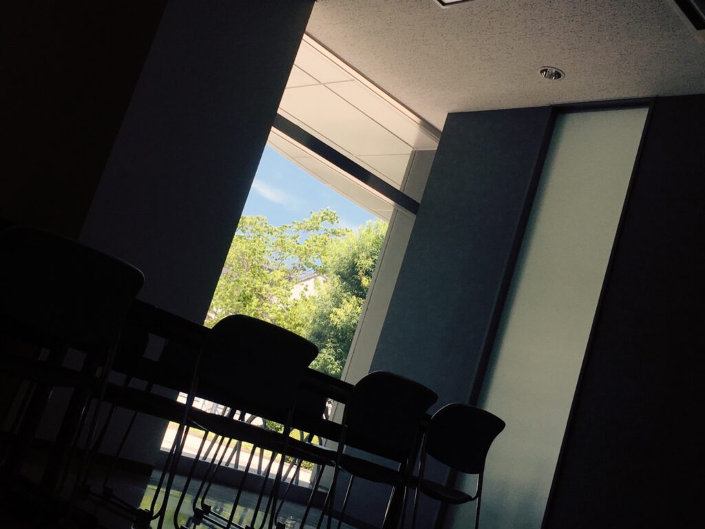 休憩室のの窓から見える外の空と木を撮影した写真。