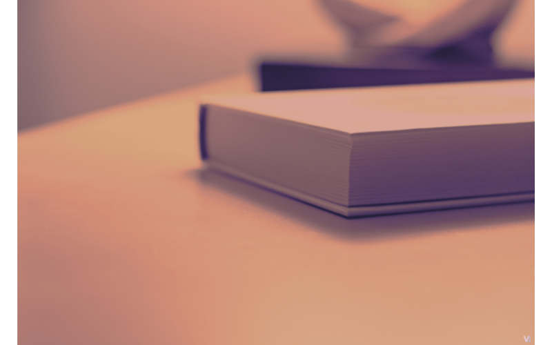 机の上に置かれた閉じた本。考えを整理し、内省する時間を表す静かなイメージ。