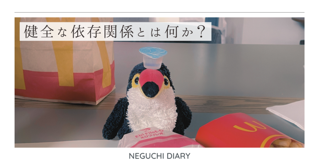 健全な依存関係をテーマにしたアイキャッチ。テーブルの上でファストフードを前に座るぬいぐるみ。