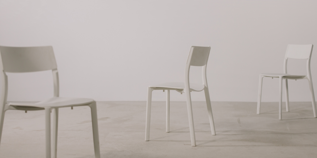 余白のある空間に、間隔をあけて置かれた白い椅子たち。静かで距離を感じる構図。