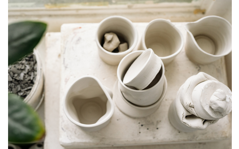 白い陶器の器やカップが並べられた作業台を上から捉えた、静かで整った印象の写真。