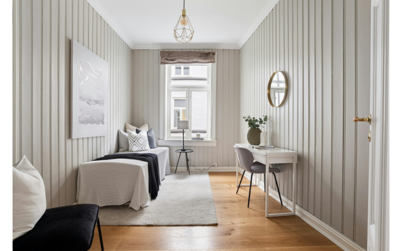 白とベージュを基調とした整った室内にベッドとデスクが配置された、静かで落ち着いた空間の写真。
