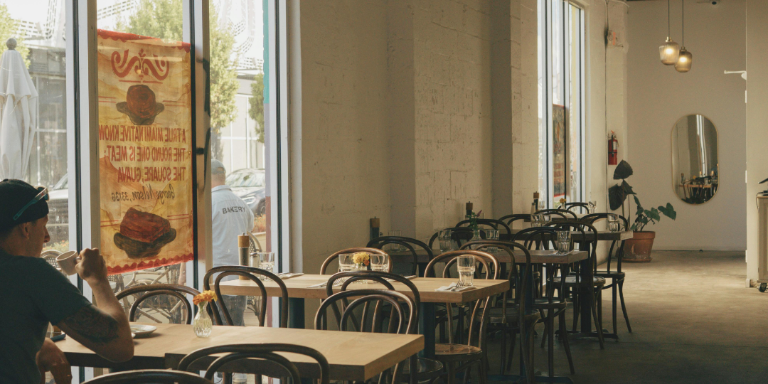 窓際のカフェで、一人静かに過ごす人と空いた席が並ぶ店内の風景。