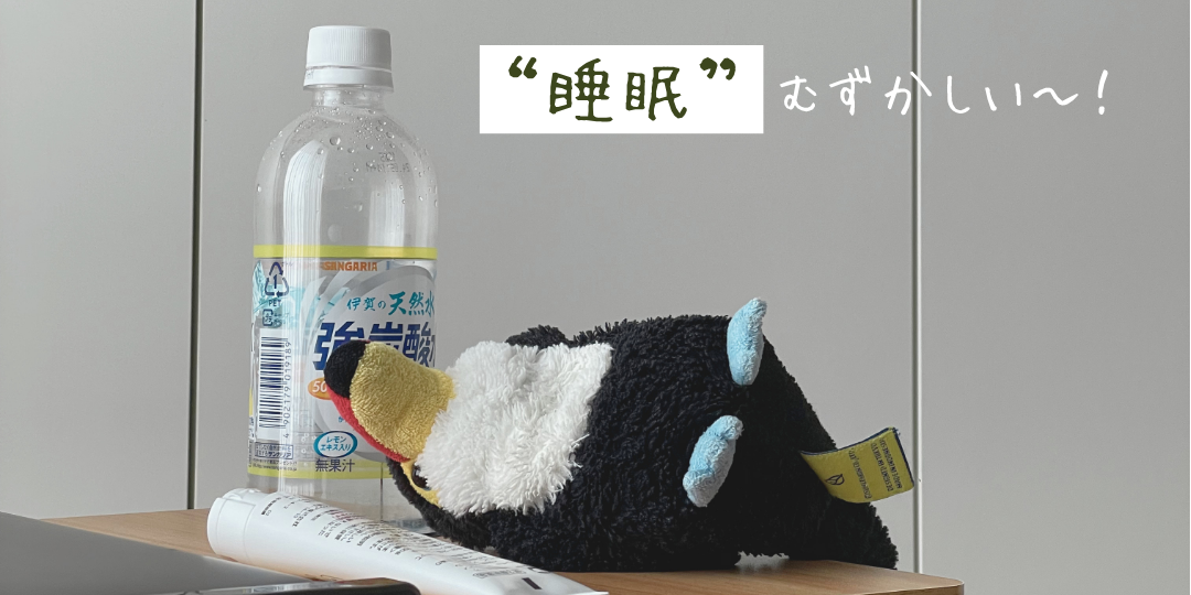 炭酸水のペットボトル横で机に突っ伏すオニオオハシのぬいぐるみ“ねぐち”。「“睡眠”むずかしい〜！」という文字が添えられ、生活リズムや睡眠問題に悩む様子を表している。