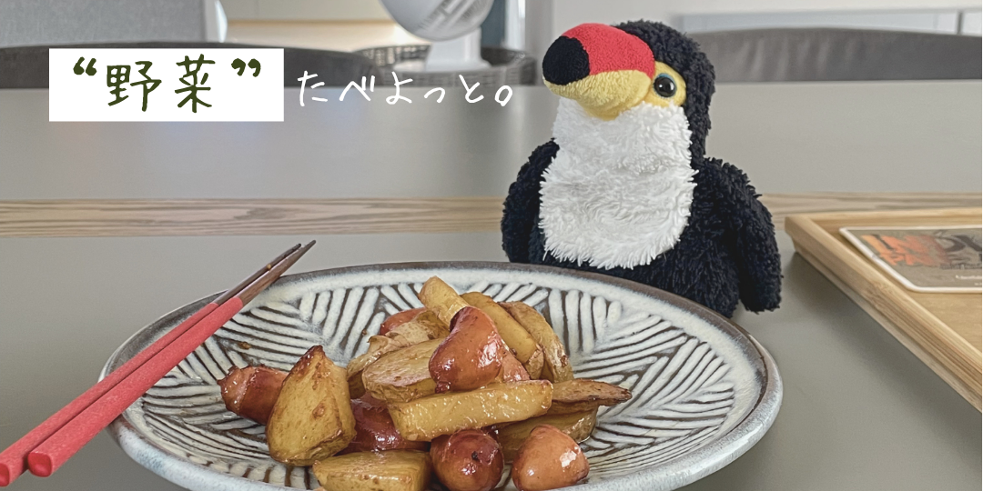 ウインナーとじゃがいもの料理が乗った皿の奥で、オニオオハシのぬいぐるみ“ねぐち”がこちらを見つめている。「“野菜”たべよっと。」という文字が添えられ、健康を意識して野菜を食べようとする様子を表している。